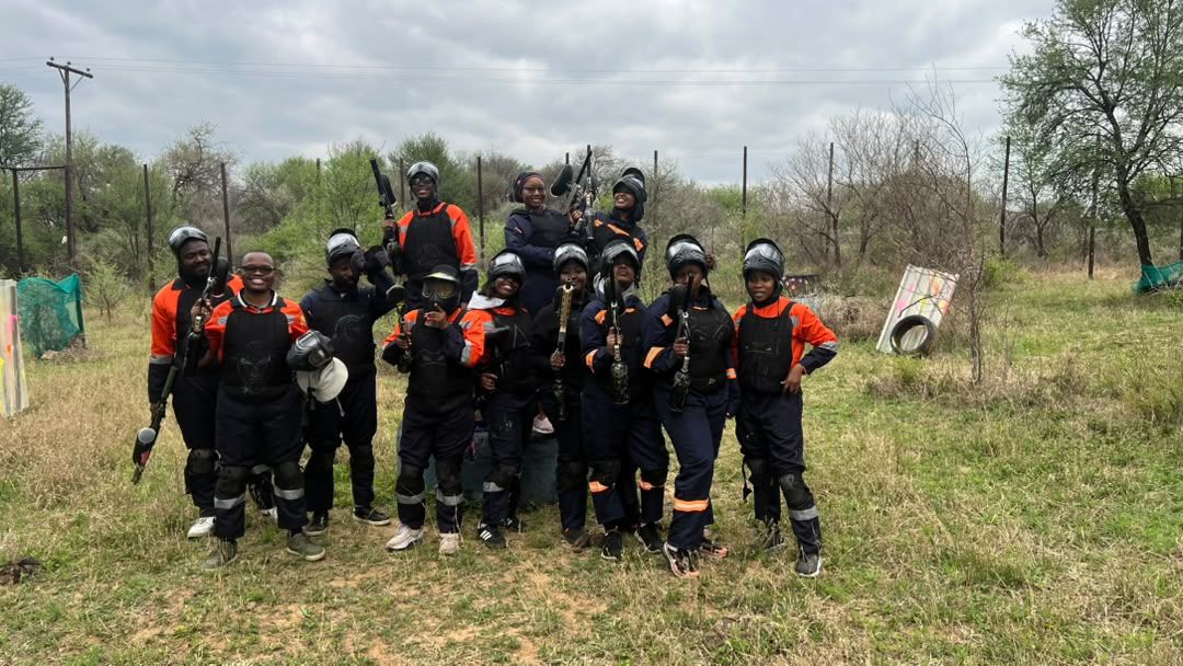Group of thirteen players in overalls and masks posing together on the field after a session
