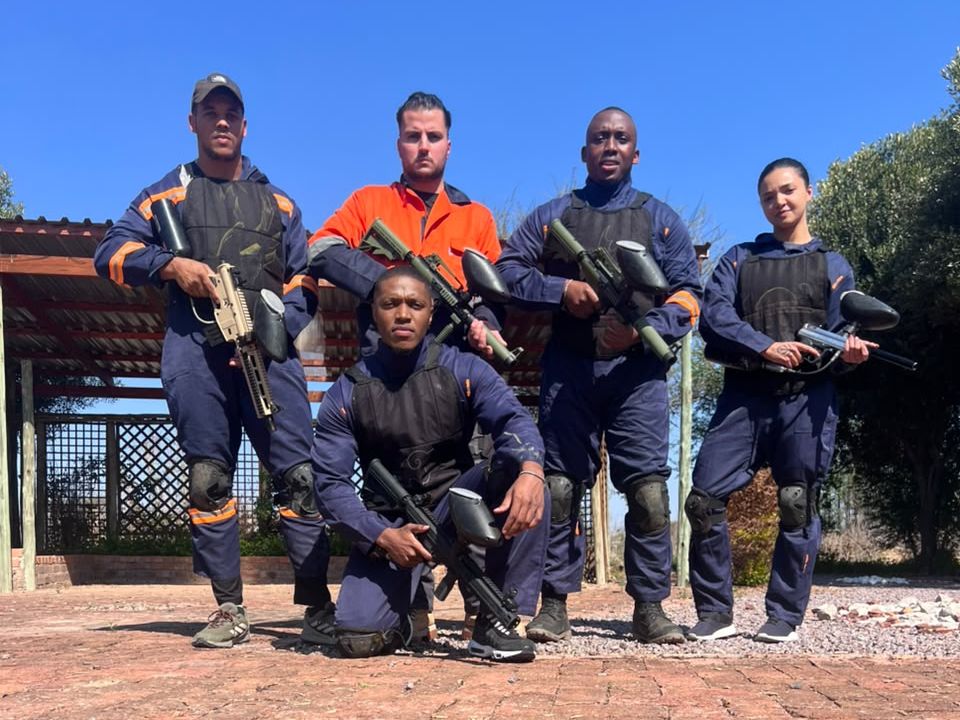 Squad of five players in full kit and overalls posing with markers at the Lion Park field